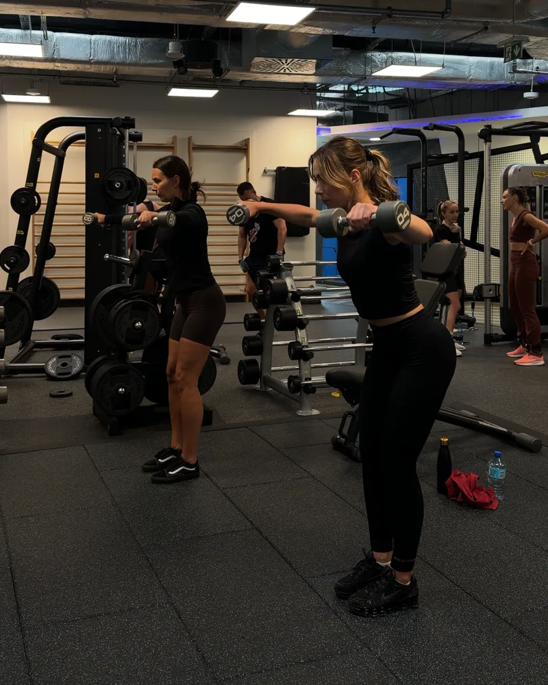 Trening w parach — dwie kobiety ćwiczą razem z hantlami